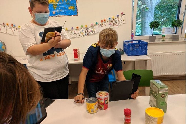 Zwei Jungen betrachten Lebensmittel und lesen Informationen darüber auf einem Computertablet. 