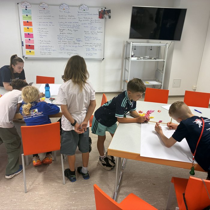 Die Kinder sind um Tische versammelt und arbeiten an ihrem Kinder- und Jugendbeteiligungsgremium.