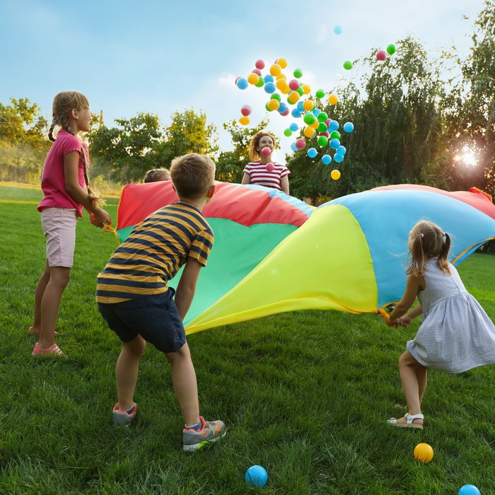 Kinder spielen mit großem bunten Tuch und Bällen