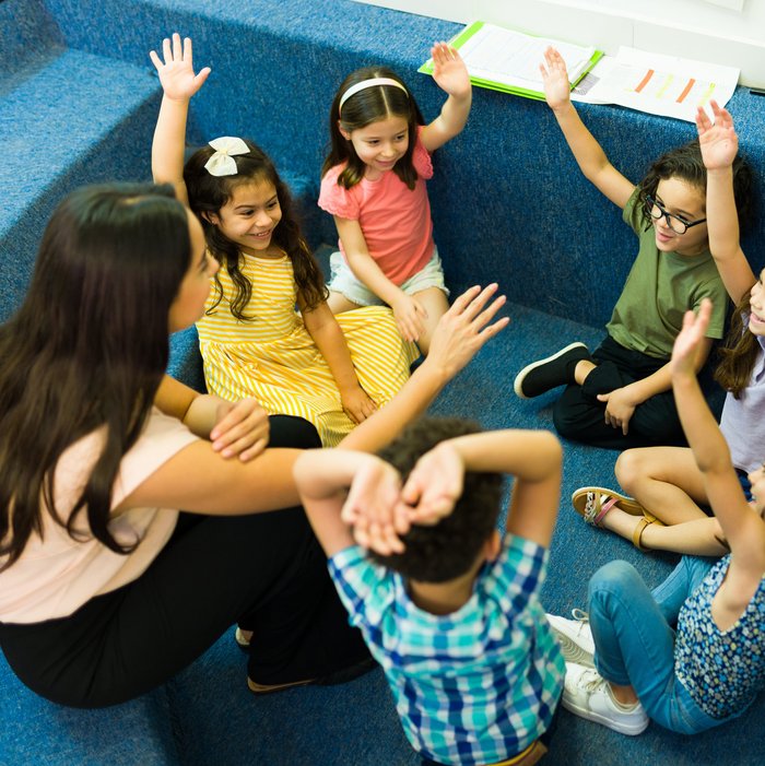 Ein Gruppe junger Kinder stimmt per Handzeichen ab. 