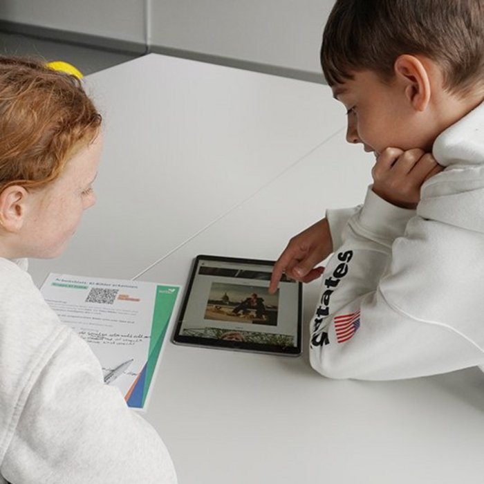 Ein Junge und ein Mädchen in weißen Pullovern schauen gemeinsam in ein Tablet. 