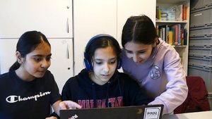 Drei Mädchen schauen gemeinsam in einen Computer. 