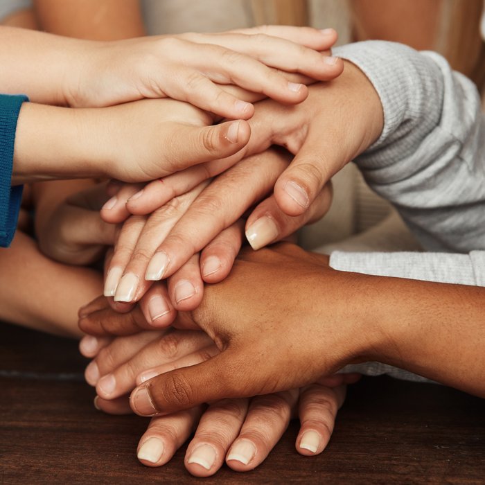 Kinder mit verschiedenen Hautfarben legen ihre Hände übereinander, man sieht nur die Hände.